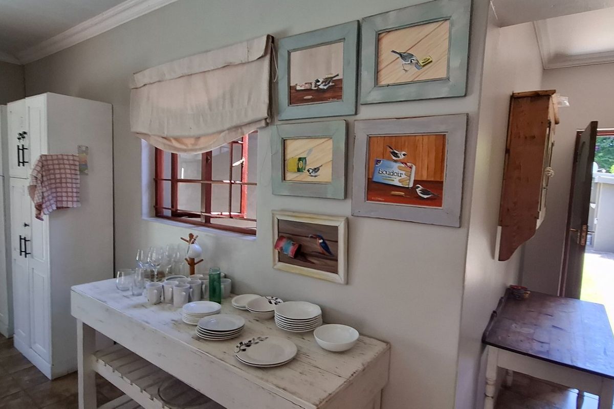 A functional kitchen area featuring built-in white cabinetry, tiled flooring, and a window with security bars, providing access to an outdoor space.