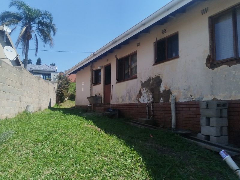Rear exterior view of the property showing significant wear to the exterior wall finish, brickwork, and window surrounds, requiring maintenance and repair.