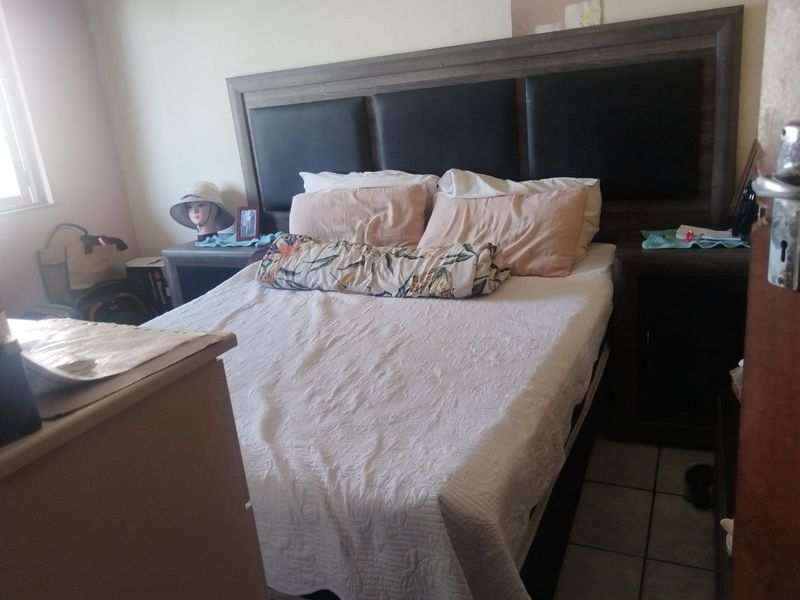 A bedroom featuring tiled flooring and a built-in headboard structure.