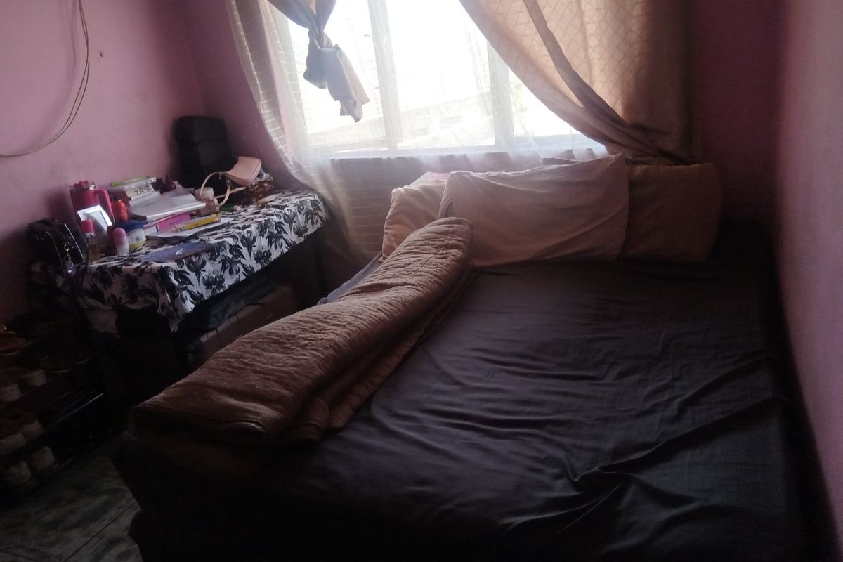 A compact bedroom featuring tiled flooring and a large window, providing natural light to the space.