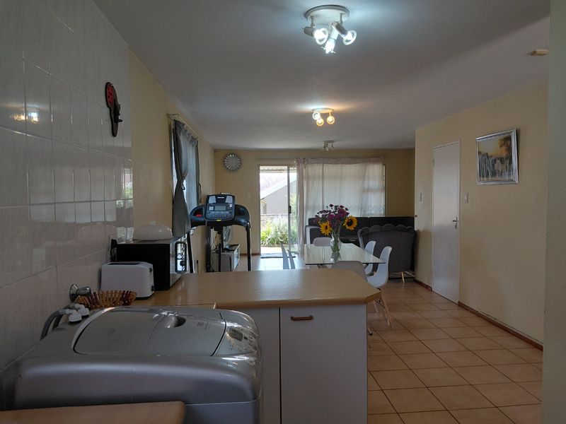 Open plan living and kitchen area featuring tiled flooring, neutral walls, and direct access to an outdoor patio through a sliding glass door.