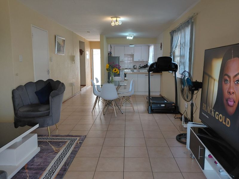 Open-plan living and dining area featuring tiled flooring and a connected kitchen with built-in cabinetry, offering a functional layout for daily living.