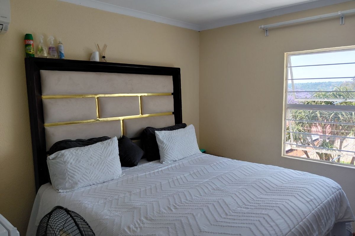 A bedroom featuring a louvered window with exterior views and coving detail.
