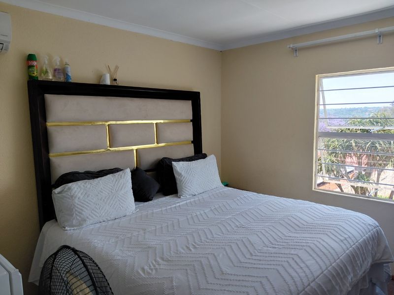 A bedroom featuring a louvered window with exterior views and coving detail.