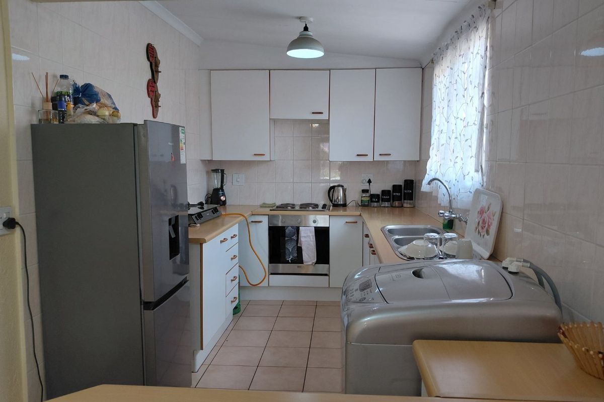 Functional kitchen featuring white cabinetry, laminate countertops, built-in oven, gas hob, and tiled splashbacks, offering a practical layout for daily meal preparation.
