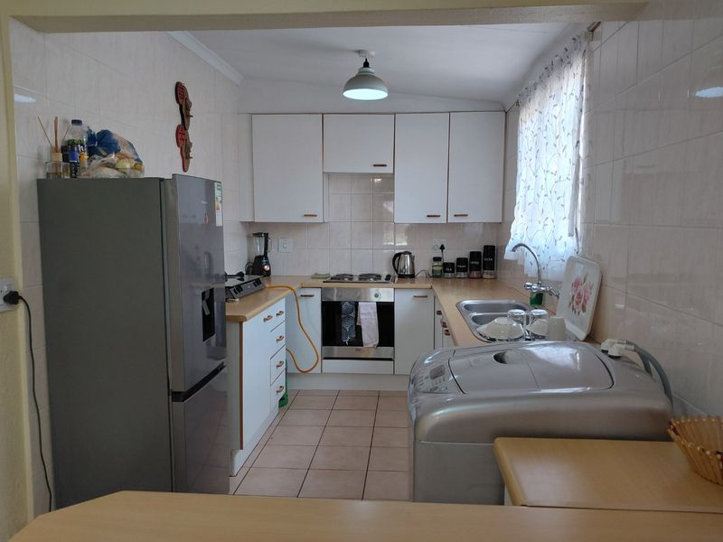 Functional kitchen featuring white cabinetry, laminate countertops, built-in oven, gas hob, and tiled splashbacks, offering a practical layout for daily meal preparation.