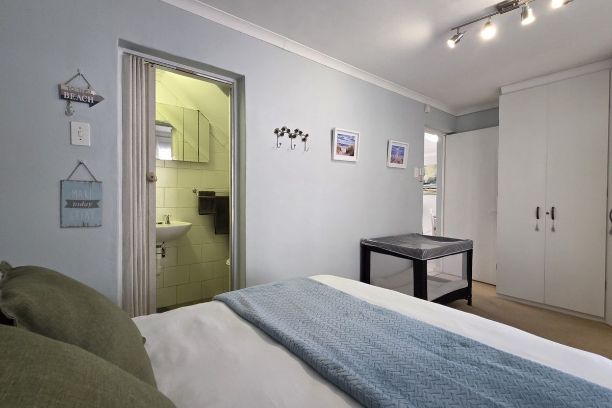 A bedroom featuring a built-in wardrobe, track lighting, and an en-suite bathroom accessed via a folding door.