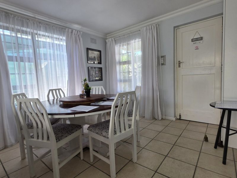 A bright dining room featuring tiled flooring, crown molding, and large sliding glass doors that provide ample natural light.