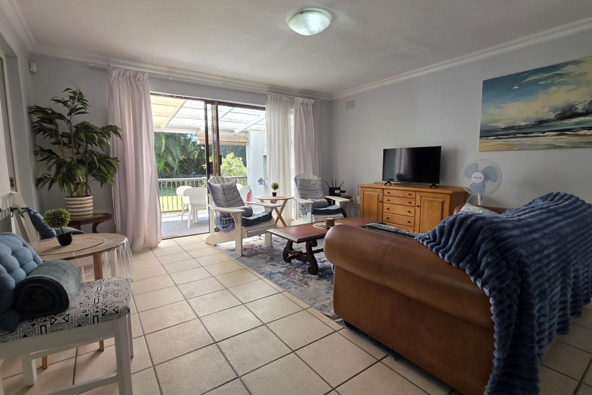 Spacious living room featuring tiled flooring and large sliding glass doors that provide direct access to the outdoor patio area.