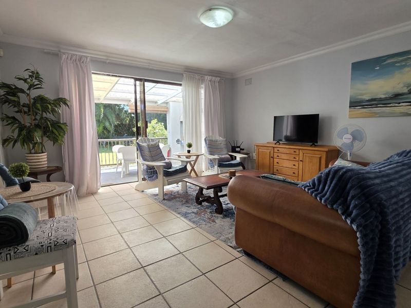 Spacious living room featuring tiled flooring and large sliding glass doors that provide direct access to the outdoor patio area.