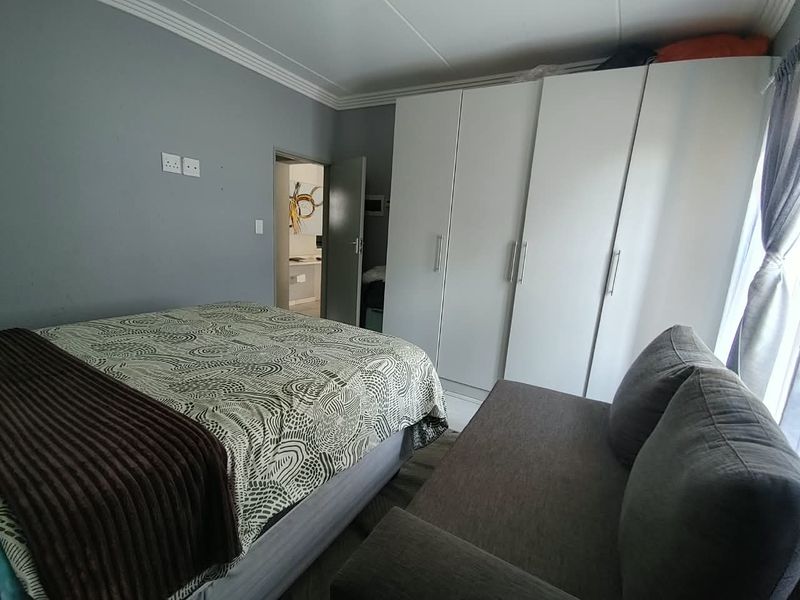 A bedroom featuring built-in cupboards, crown molding, and neutral grey wall finishes, providing a functional and well-organized sleeping space.