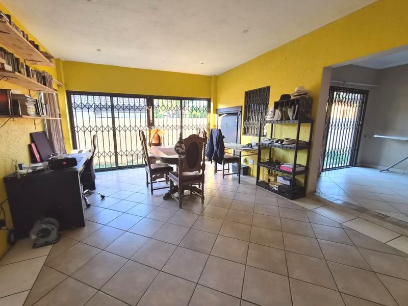 Spacious living area featuring tiled flooring, recessed lighting, and large sliding glass doors with security gates, offering direct access to the exterior.