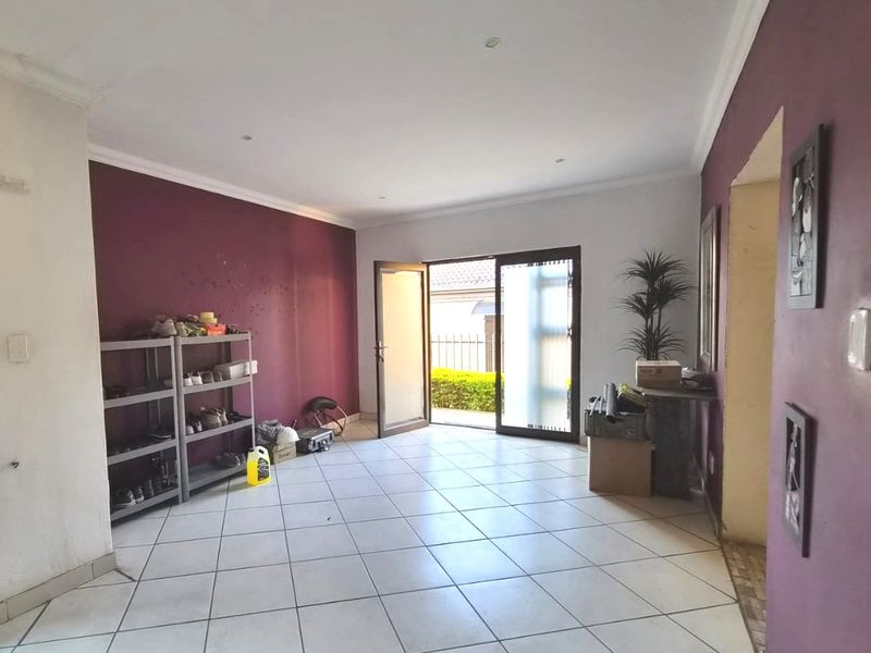 A living room featuring tiled flooring, recessed downlights, and a sliding glass door providing access to the exterior.
