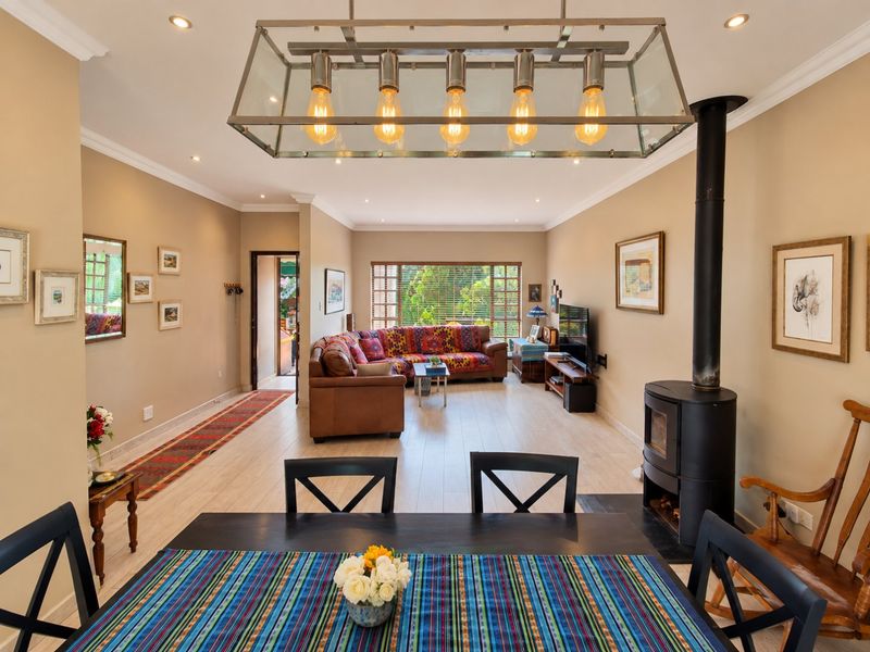 Spacious open-plan living and dining area featuring modern laminate flooring, a wood-burning fireplace, and elegant recessed lighting throughout.