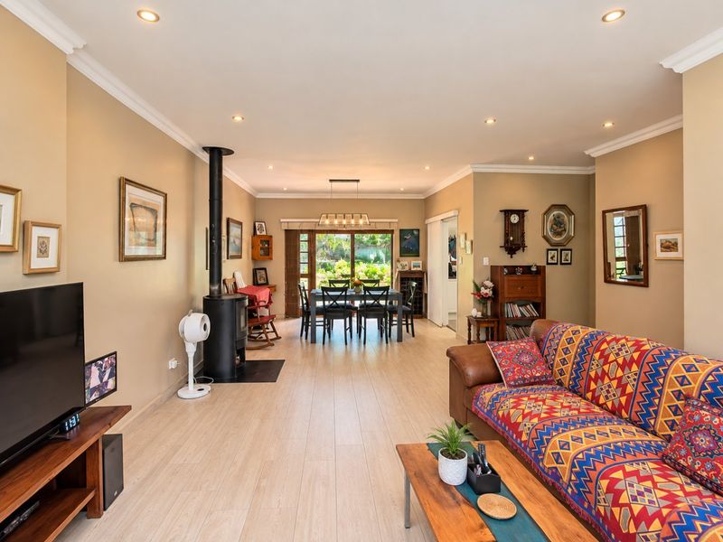 Spacious open-plan living and dining area featuring a wood-burning fireplace, recessed lighting, and sliding glass doors leading to the garden.
