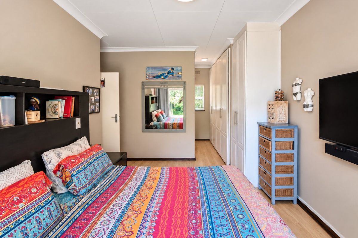 A well-maintained bedroom featuring built-in cupboards, laminate flooring, and neutral wall tones, providing a functional and comfortable living space.