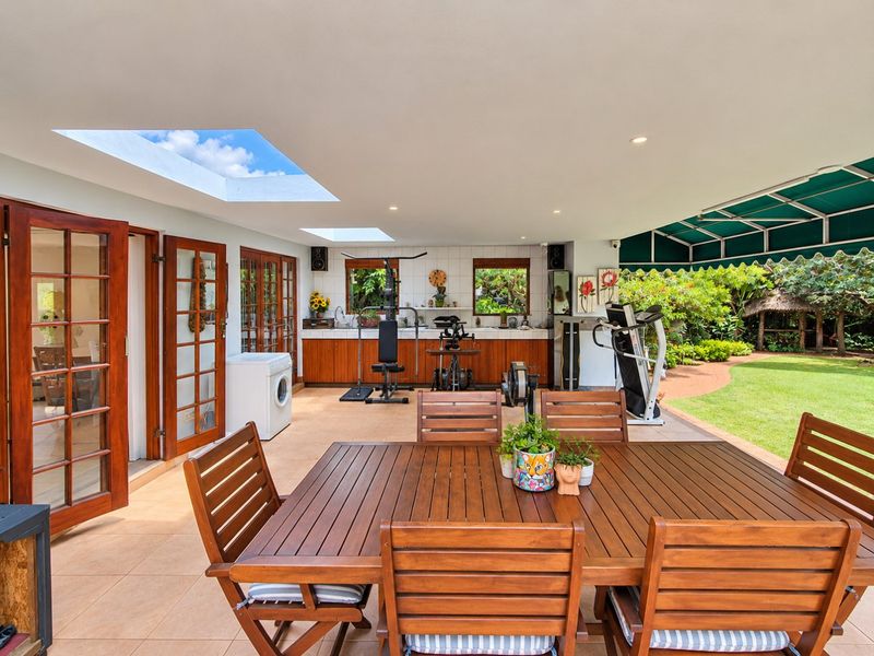 Spacious covered patio featuring tiled flooring, built-in cabinetry, skylights, and direct access to the garden, ideal for outdoor entertaining and versatile use.