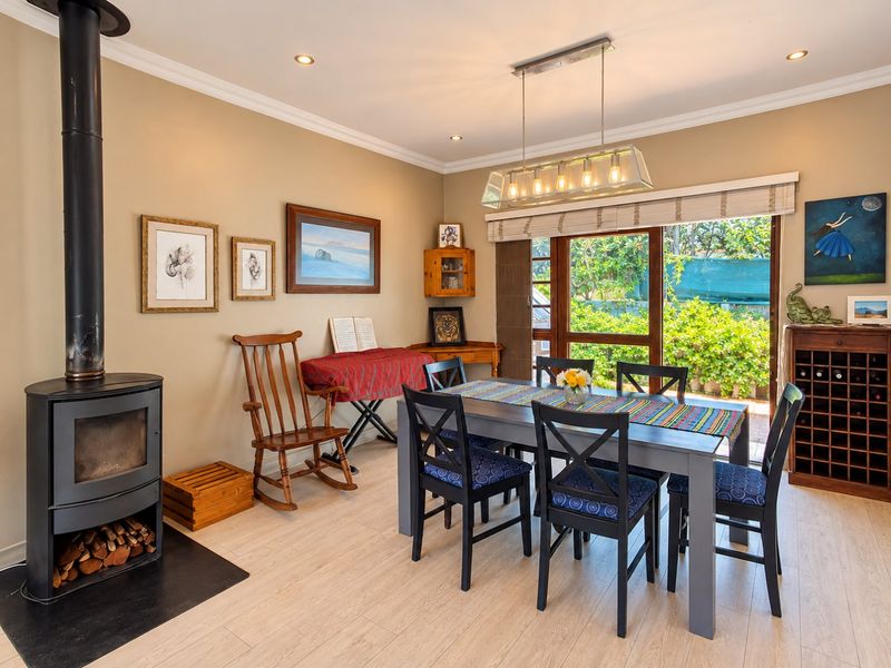 A bright dining room featuring a modern freestanding fireplace, laminate flooring, and large sliding glass doors that provide direct access to the garden.
