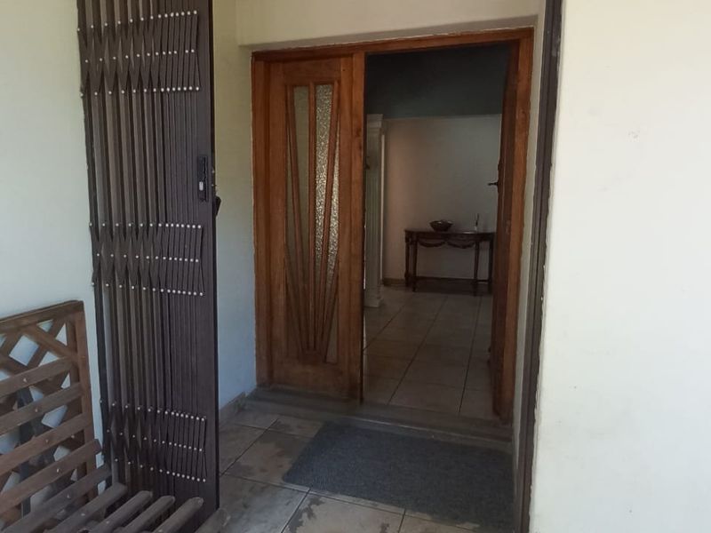 Entrance area featuring a security gate and wooden front door leading into the home with tiled flooring.