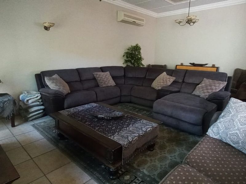 A spacious living room featuring tiled flooring, coved cornicing, and a wall-mounted air conditioning unit.