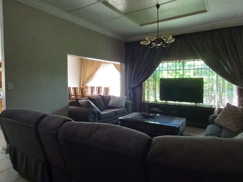Spacious open-plan living area featuring tiled floors, a recessed ceiling, and an adjacent kitchen with built-in cabinetry and oven.