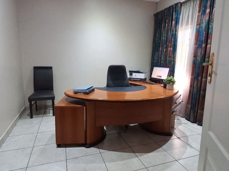 A functional home office space featuring tiled flooring and window treatments, providing a dedicated area for work or study.