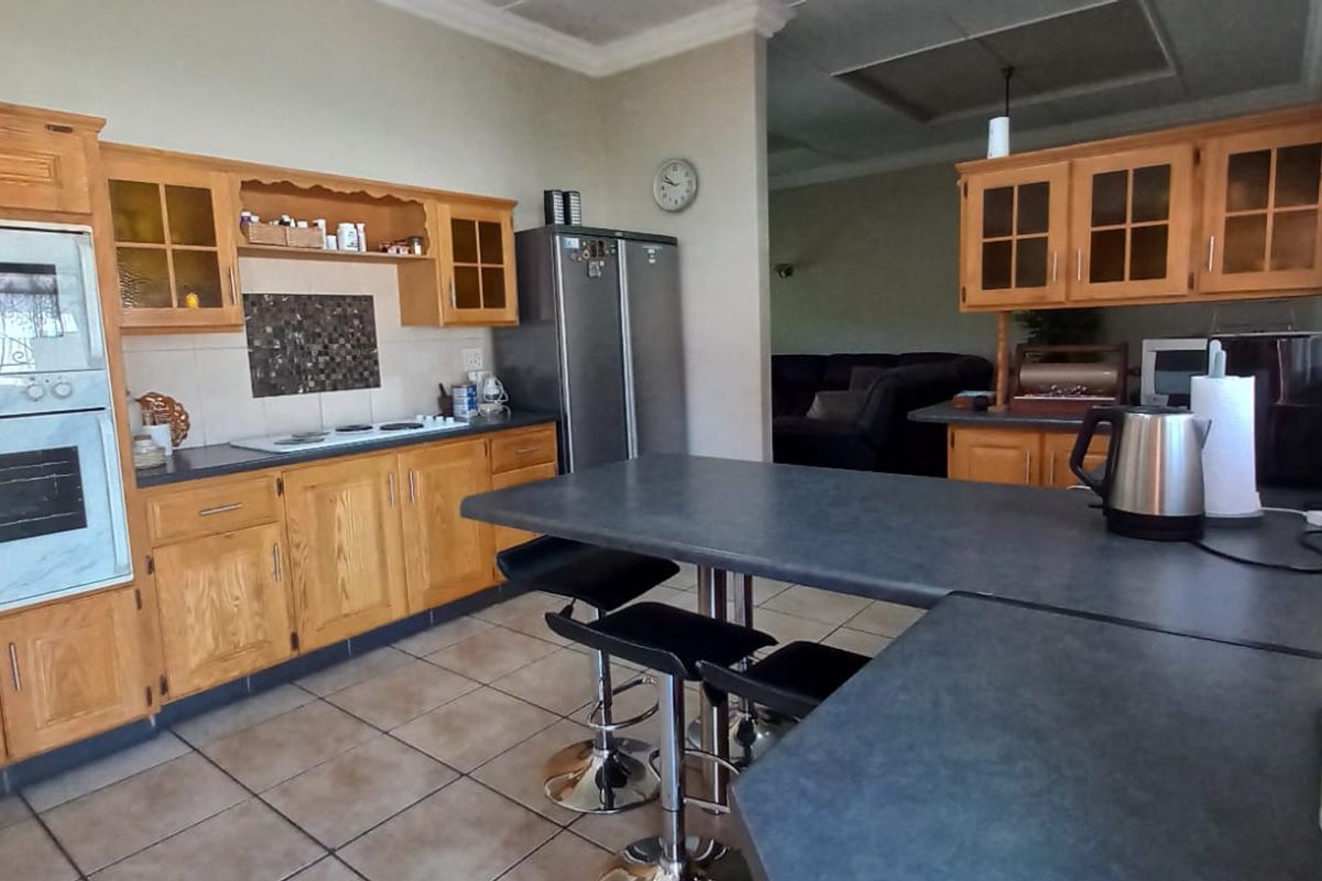 A functional kitchen featuring wooden cabinetry, built-in oven and microwave, tiled flooring, and a breakfast bar area with direct access to the living space.