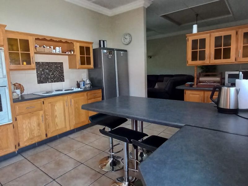 A functional kitchen featuring wooden cabinetry, built-in oven and microwave, tiled flooring, and a breakfast bar area with direct access to the living space.