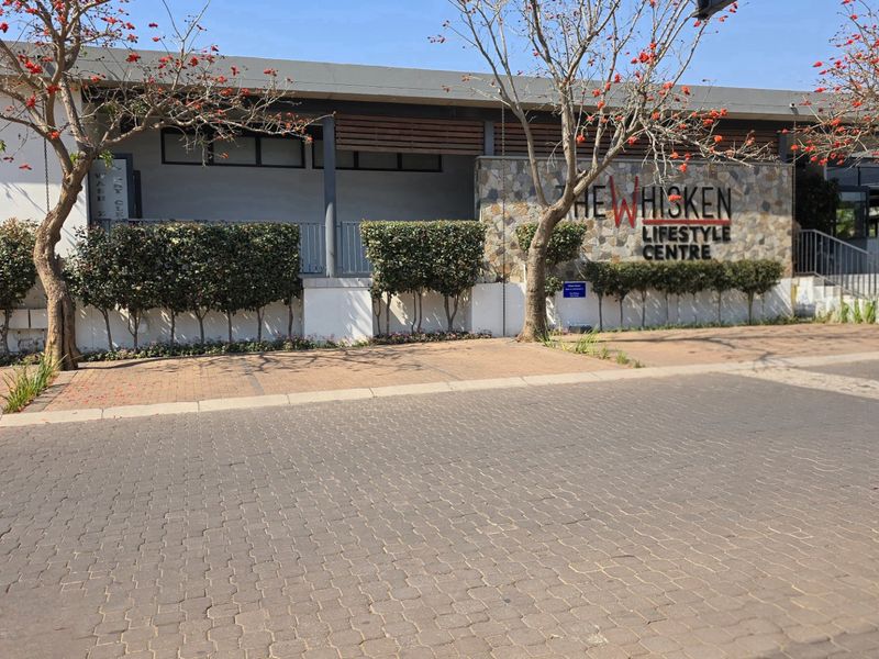 Exterior view of The Whisken Lifestyle Centre, featuring stone cladding, paved driveway, and well-maintained landscaping.