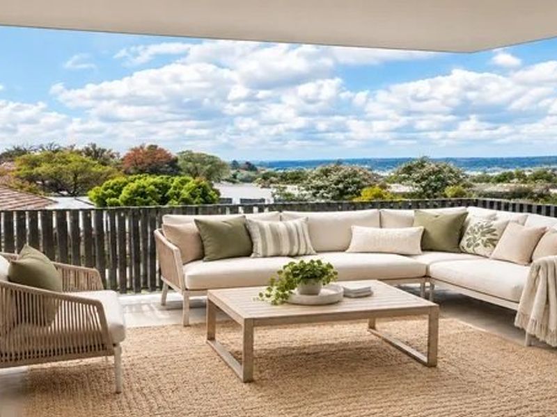 A spacious covered balcony featuring tiled flooring and a modern vertical slat balustrade, offering expansive outdoor views.