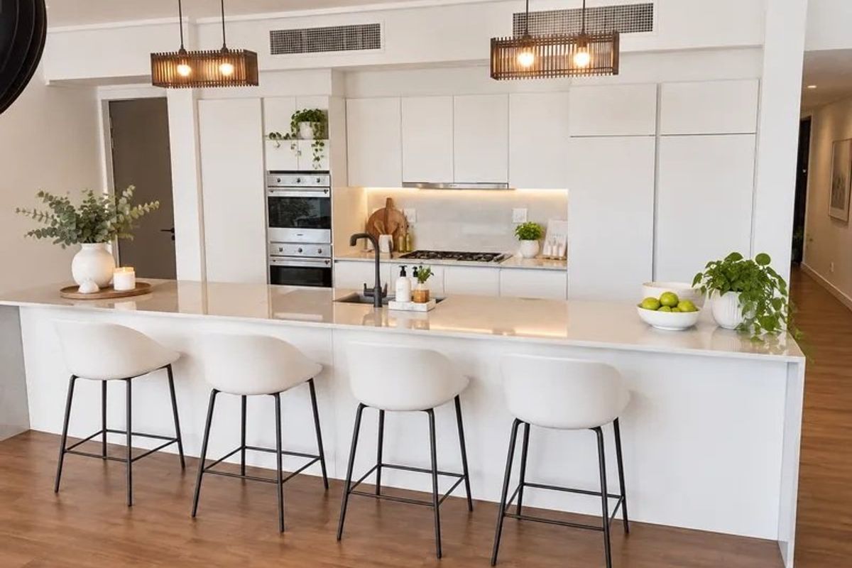 Modern kitchen featuring a large stone island, integrated appliances, sleek white cabinetry, and recessed ducted air conditioning in an open-plan layout.