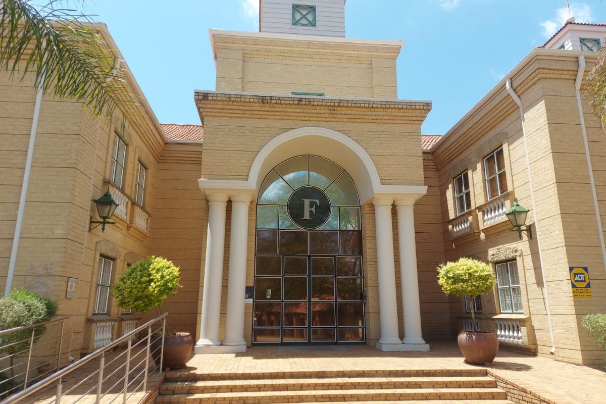 The front facade of the commercial building features a prominent arched entrance with classical columns, brick masonry, and paved access steps.