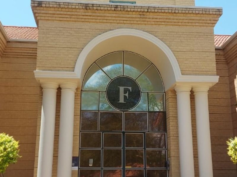 The front facade of the commercial building features a prominent arched entrance with columns, brick exterior, and decorative balustrades.
