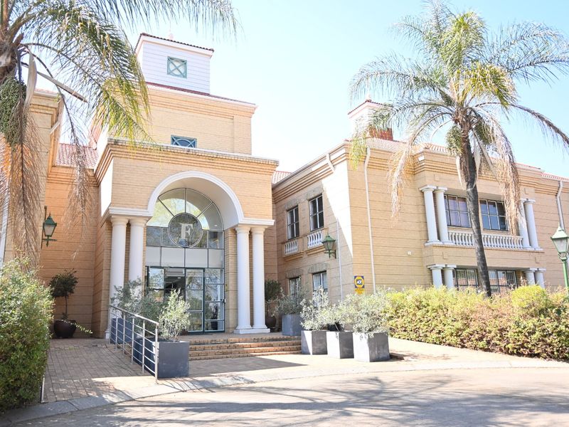 A well-maintained commercial building facade featuring classic architectural elements, brick masonry, an arched entrance, and a prominent tower structure.