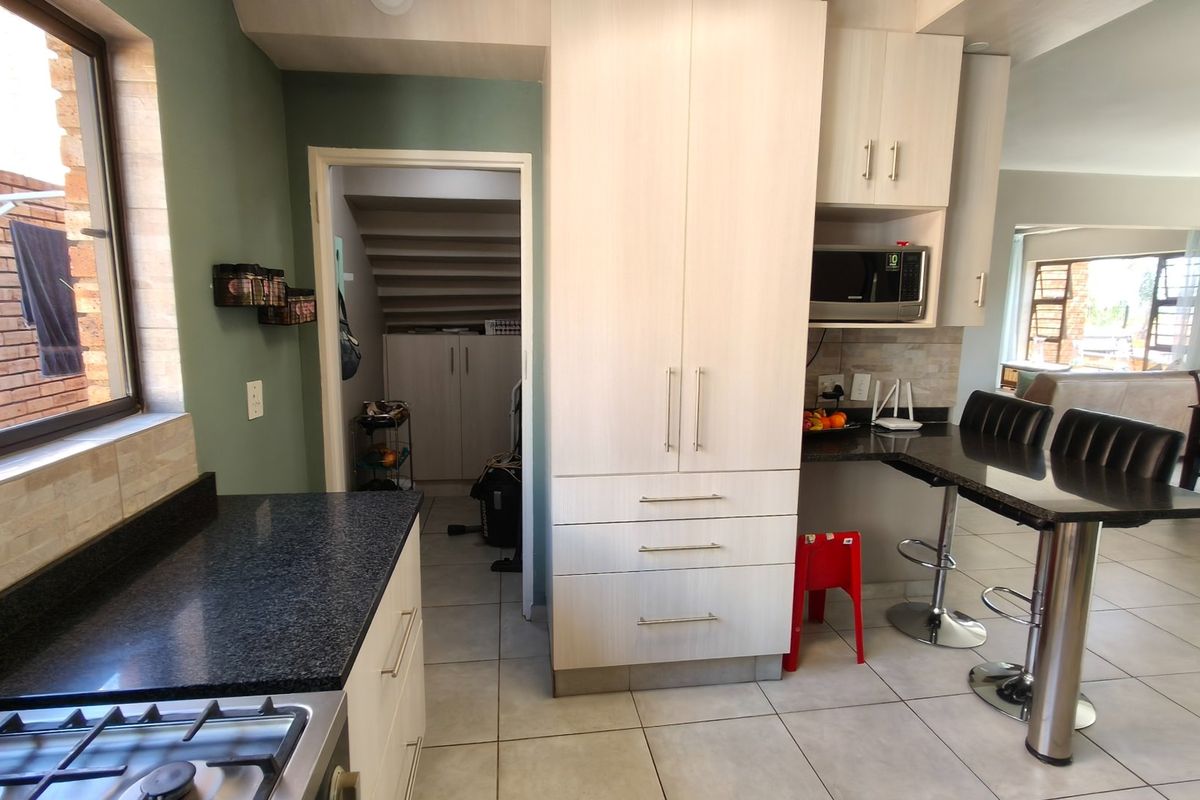 Modern kitchen featuring light wood cabinetry, granite countertops, a gas hob, and a breakfast bar, seamlessly flowing into the adjacent living area.
