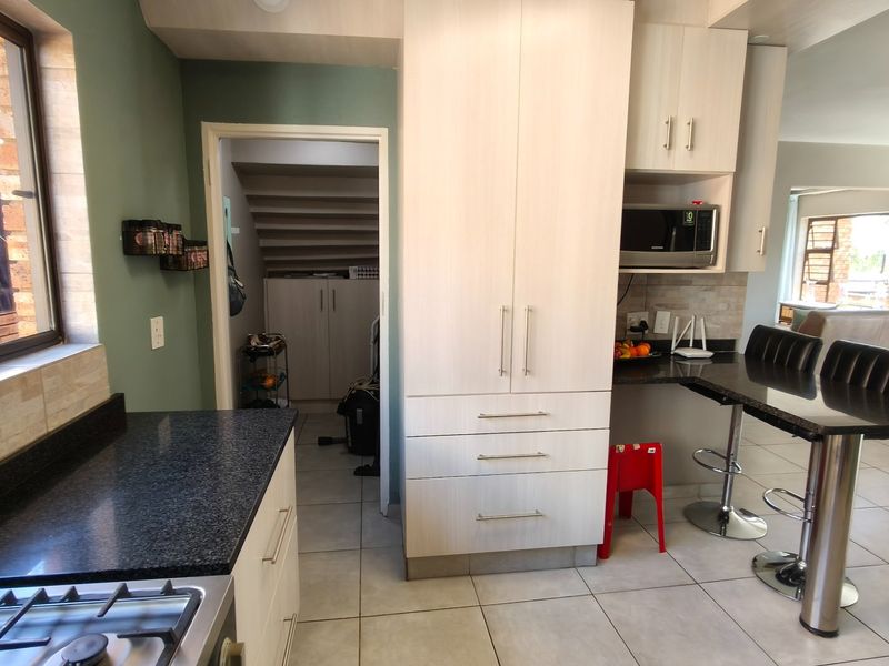Modern kitchen featuring light wood cabinetry, granite countertops, a gas hob, and a breakfast bar, seamlessly flowing into the adjacent living area.