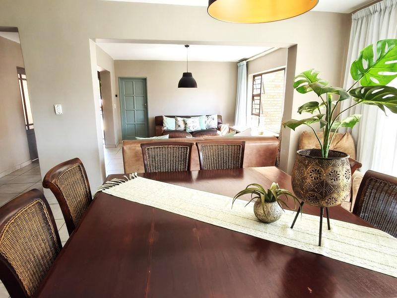 Spacious open-plan dining and living area featuring neutral wall tones, tiled flooring, and natural light through large sliding glass doors.