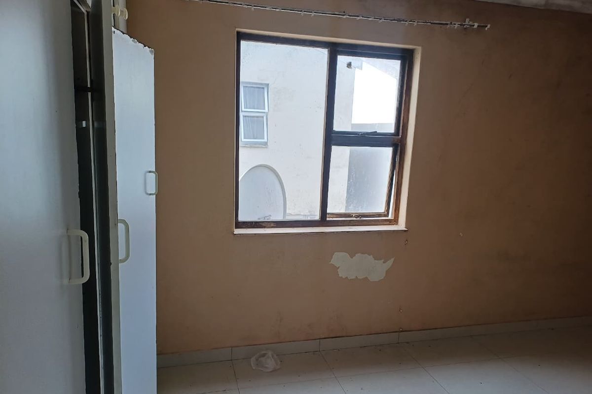 An empty bedroom featuring built-in cupboards and tiled flooring, requiring cosmetic updates to the walls and ceiling to restore its condition.