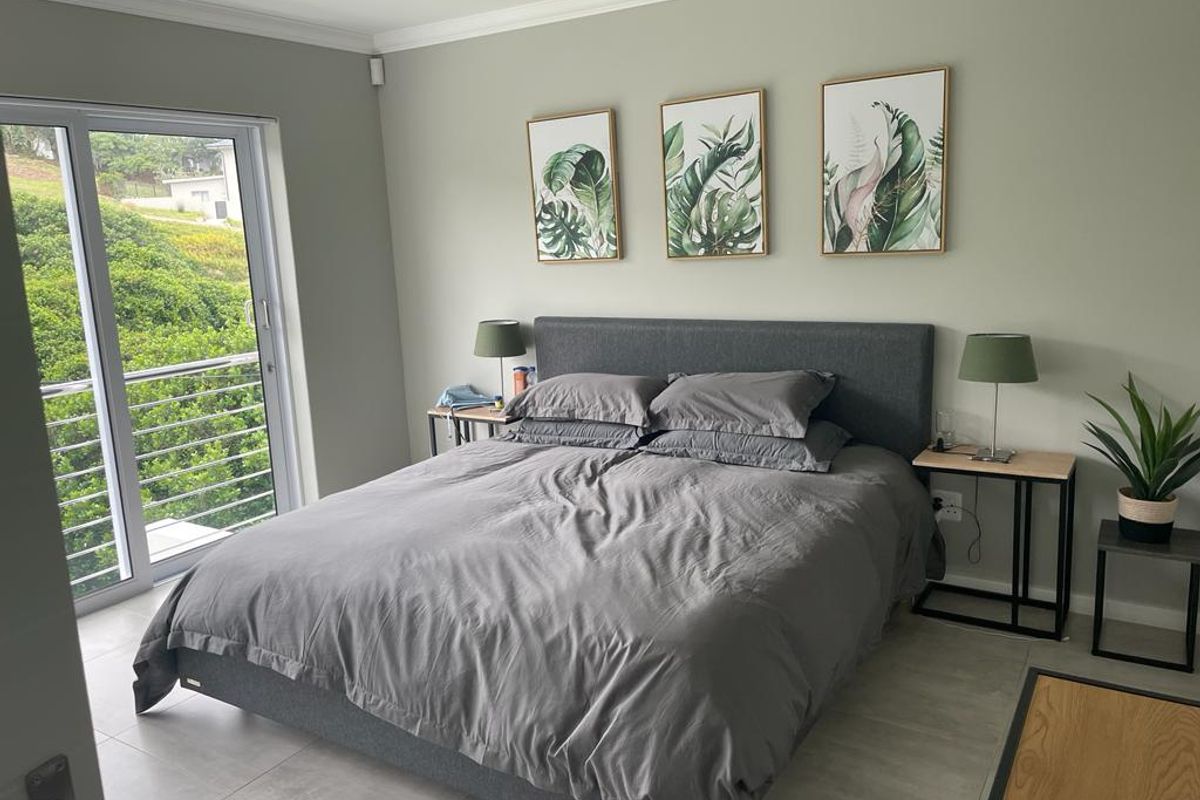 A well-maintained bedroom featuring neutral wall tones, tiled flooring, and a sliding glass door providing access to an outdoor area.