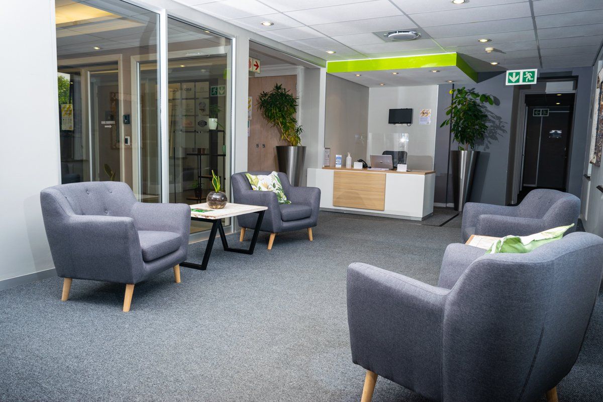 A professional commercial reception area featuring a modern reception desk, glass-partitioned office spaces, and integrated ceiling lighting.
