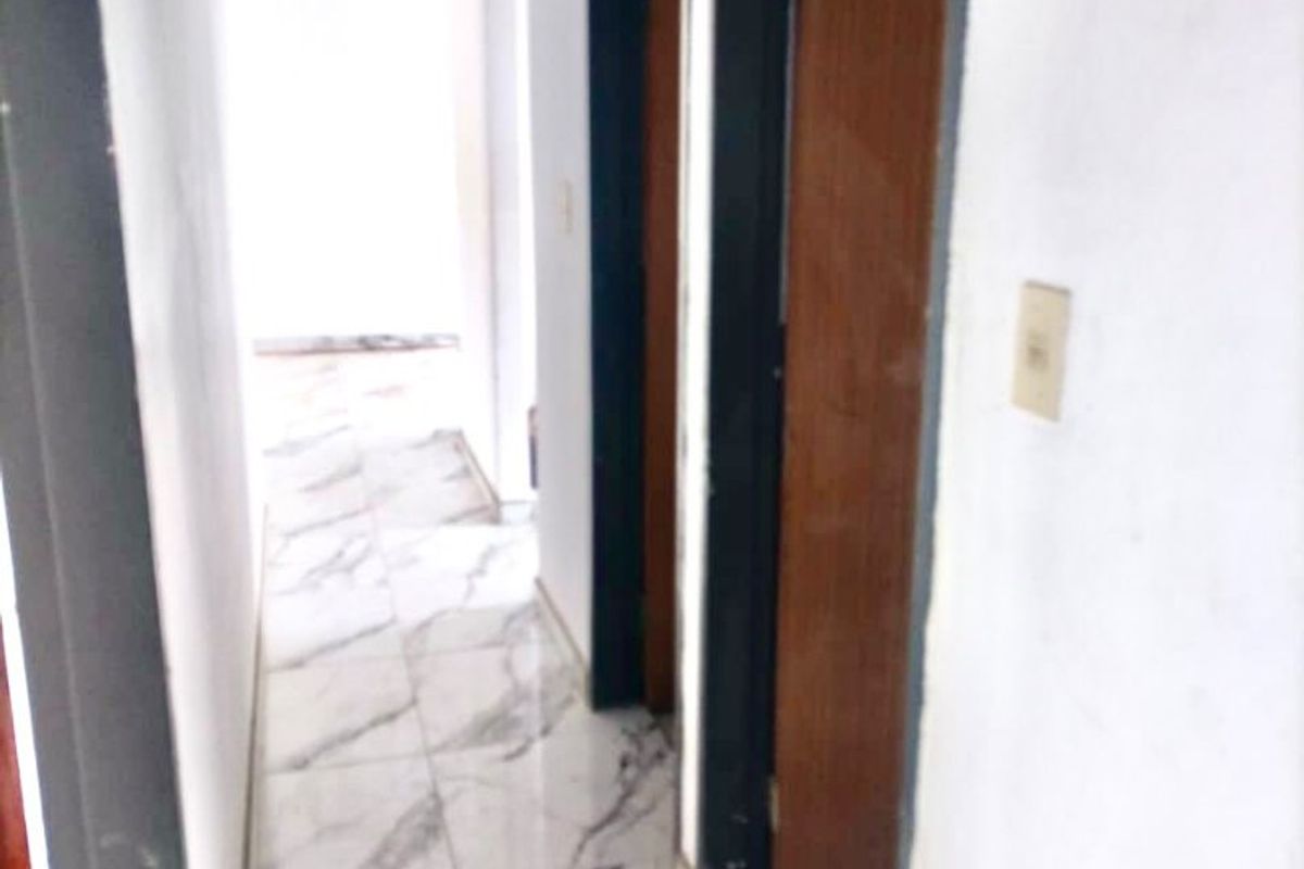 A narrow hallway featuring marble-look floor tiles and multiple doorways, requiring minor cosmetic attention to finishes.