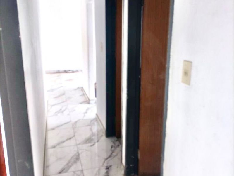 A narrow hallway featuring marble-look floor tiles and multiple doorways, requiring minor cosmetic attention to finishes.