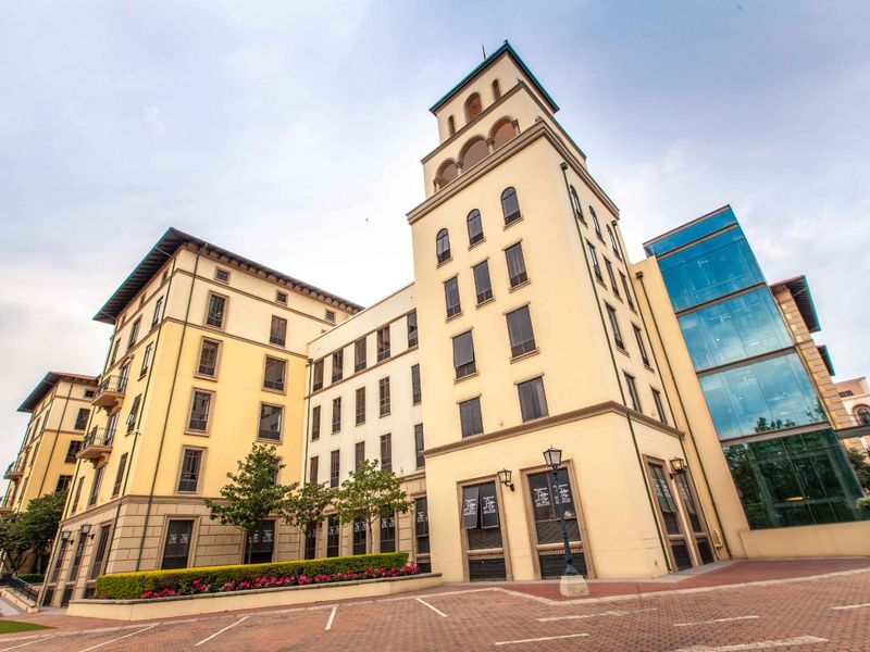 A professional exterior view of a multi-story commercial building featuring a prominent tower, glass facade elements, and well-maintained paved surroundings.