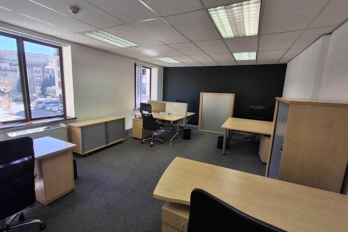 A functional commercial office space featuring suspended ceilings, recessed lighting, carpeted flooring, and large windows providing natural light.