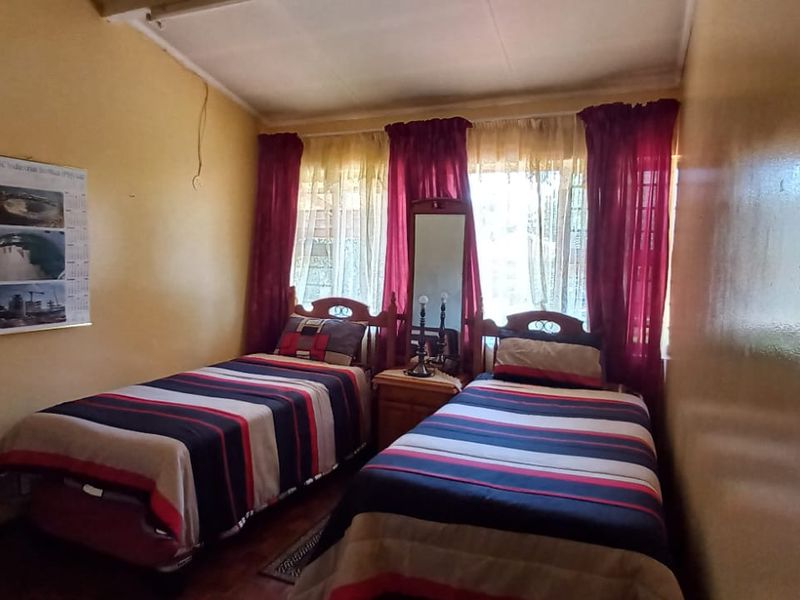 A compact bedroom featuring a sloped ceiling and window security bars, requiring cosmetic updates to improve the overall finish and appeal.