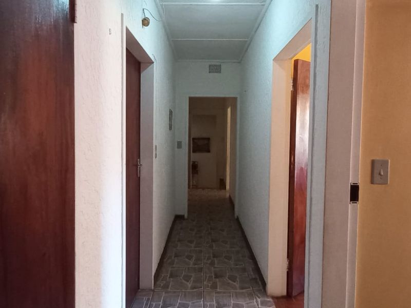 A functional hallway featuring tiled flooring and multiple solid wood doors providing access to various rooms within the home.