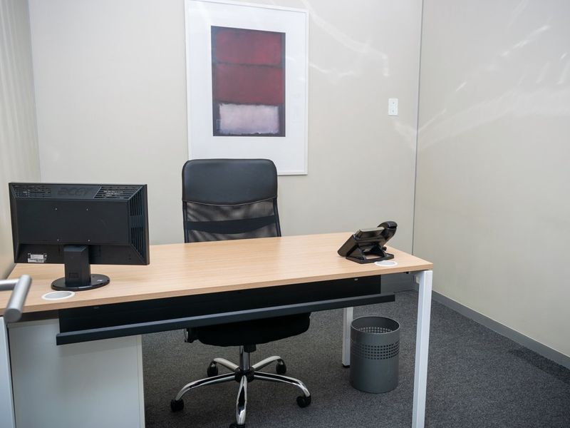 A clean and functional commercial office space featuring neutral wall finishes and carpeted flooring.