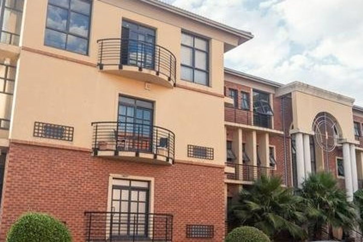 A multi-story commercial building featuring a combination of brick and plaster facade, external staircases, and multiple balconies with metal railings.