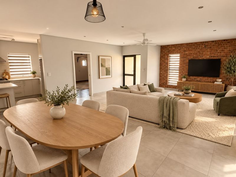 Spacious open-plan living area featuring a modern kitchen with island, dining space, and a lounge area with an exposed brick feature wall.