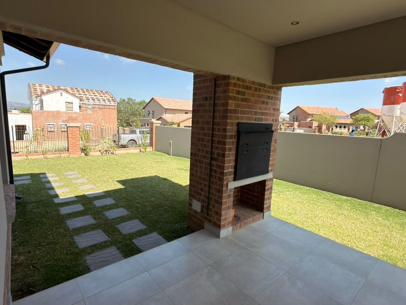 Covered patio area featuring a built-in braai, tiled flooring, and direct access to the private garden.